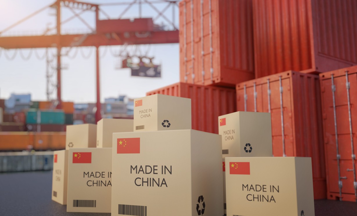 Groupe de 3 personnes regardant une tablette dans un environnement de travail, avec des colis emballés