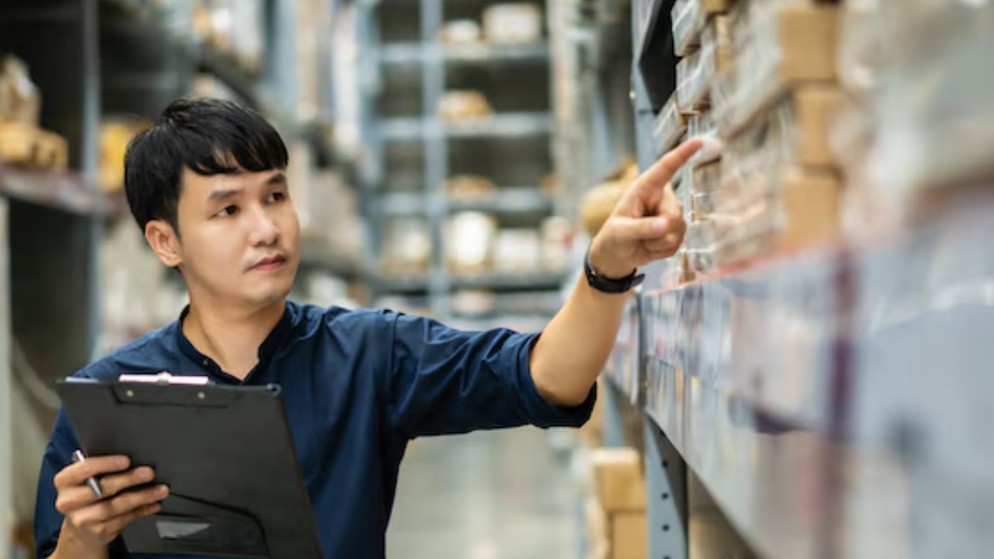 Groupe de 3 personnes regardant une tablette dans un environnement de travail, avec des colis emballés